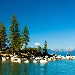 Clear alpine lake ringed by pines beneath Sierra Nevada granite peaks