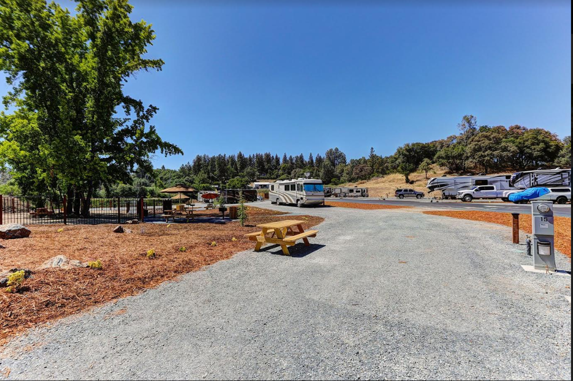 Spacious pull-through RV site at Auburn RV Resort with a concrete pad and wooden picnic area